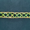 A necklace made of crossed green strands of beads bordered by gold rails in a net-like pattern