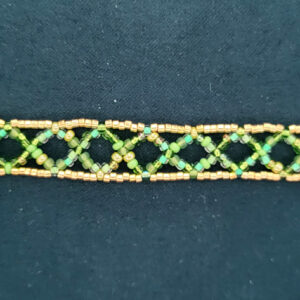 A necklace made of crossed green strands of beads bordered by gold rails in a net-like pattern