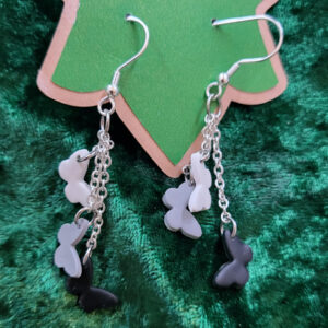 Earrings dangling white, grey and black butterflies from silver chain at various levels.